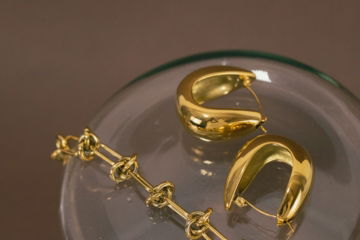a-pair-of-gold-earrings-sitting-on-top-of-a-glass-container.jpg a pair of gold earrings sitting on top of a glass container